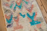 A close-up of the Moroccan rug's soft, even pile with abstract turquoise and dusty rose motifs.