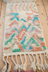 Plush, hand-knotted pile of a Moroccan rug with abstract turquoise and dusty rose motifs.