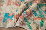 A fold in the Moroccan rug reveals the plush, hand-knotted pile in soft, colorful shades.