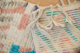 Close-up of a Moroccan rug's plush pile beside its woven back with braided ivory tassels.