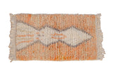 Hand-knotted Moroccan rug with an abstract diamond design on a shaggy, pale terracotta pile.