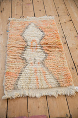 Angled view of a Moroccan rug with an abrashed terracotta ground and thick pile.