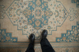The soft, worn texture of a vintage Oushak rug with a sky blue and beige medallion design.