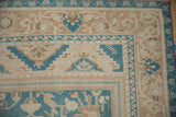 Stepped corner spandrel and meandering vine border on a distressed Oushak in dusty blue and sand tones.