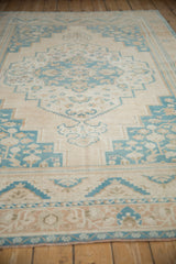 Worn texture and stepped medallion of a vintage Oushak carpet seen from a low angle.