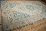 Low angle across a vintage distressed Oushak carpet showing its layered border and worn pile.