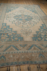 Low angle view of the distressed Oushak carpet's stepped medallion and border.