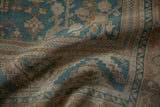 Soft, low-profile pile of a distressed Oushak carpet in dusty blue and sand tones.
