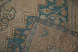 Corner of a vintage Oushak carpet folded to display the back weave and machine-bound edge.