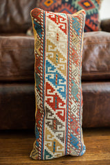 Hand-knotted geometric pattern in red, blue, gold on antique Caucasian pillow.