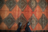 Distressed Kurd runner: abrashes rust field, serrated diamond medallions in charcoal and silver.