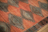 Distressed terracotta field of vintage Kurd rug with serrated diamond medallion and geometric border.