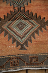 Distressed Kurd rug runner showing geometric border and worn dusty rust field.