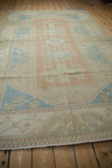 Distressed vintage Dosemealti carpet showing faded floral patterns in dusty rose and pale blue.