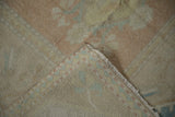 Distressed dusty rose pile showing worn knot heads and hand-knotted foundation with bound edge.