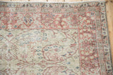 Corner view of a vintage Sparta carpet showing the thousand flower border in dusty red and charcoal.