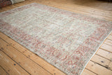 Angled view of a distressed Sparta carpet highlighting the faded patina on its scrolling vine design.