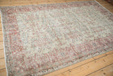 Angled view of a distressed Turkish carpet with a faded allover floral vinery design.