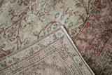 Machine-bound edge and low, worn pile on the corner of a vintage distressed Sparta carpet.
