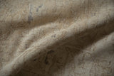 Close-up view of the distressed carpet's low-pile texture and exposed foundation in beige.