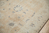 Distressed Sparta carpet close-up, worn navy floral on sandalwood, foundation visible, bound edge.