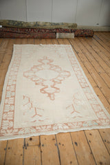 Angled close-up of distressed vintage Oushak rug with pale copper germinating plant border.