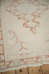 Close-up of distressed vintage Oushak rug, faded copper patterns and even pile wear.