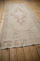 Distressed Oushak rug runner border in pale copper and turquoise germinating plant motif on ivory.