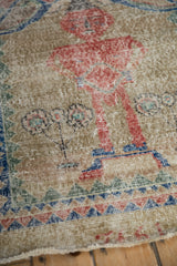 A pictorial human figure in dusty red on the distressed, low-pile of a vintage Sparta rug.