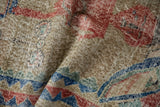 Close-up on the distressed vintage rug showing wear to knot heads and exposed foundation.