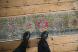Distressed Sampler Oushak runner with repeating magenta florals and worn pile.