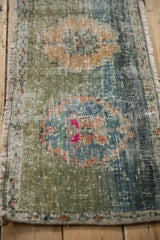 Distressed edge of the Oushak rug, showing narrow seed motif border and color abrash.