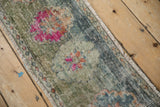 Distressed vintage Oushak rug runner edge, showing faded green, blue hues, and exposed foundation.