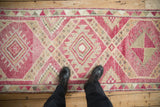Standing on a vintage distressed Kurd runner looking down its pink geometric pattern.