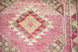 Close-up on the distressed, hand-knotted pile of a Kurd rug, showing a serrated gul in magenta and platinum.