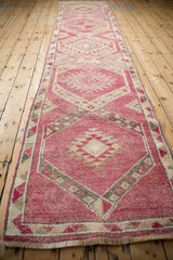 Angled view down the length of a distressed Kurd runner with magenta geometric medallions.
