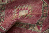 The textured, hand-knotted wool pile of a vintage Kurd rug in magenta and ivory.