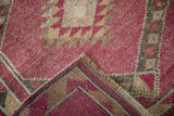A vintage Kurd rug's machine-bound corner reveals its hand-knotted back and worn magenta pile.