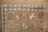 Corner of a distressed Kars rug with a scrolled tendril border and short, hand-knotted pile.
