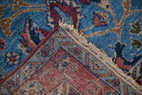 A folded corner reveals the hand-knotted weave and plush pile of a vintage Bibikabad rug.
