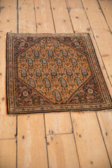 Angled view of a vintage Sarouk rug showing its repeating paisley design on a saffron field.