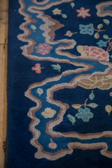 Art Deco river ribbon border on cobalt blue, with scattered pale blossoms.