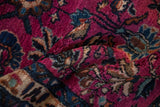 Plush magenta and deep indigo floral blossoms with scrolled leaves on a vintage Lilihan rug.