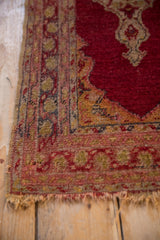 Tattered fringe and worn side of vintage Anatolian rug, highlighting meandering vine border.