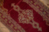 Vintage Anatolian rug mat detail shows book cover corner spandrel with meandering vine, black cherry red, saffron yellow. Tatter to side.