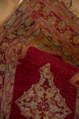 Textured pile and tattered edge detail of a vintage Anatolian rug in black cherry red.