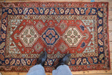 A vintage Persian Heriz rug with geometric medallions shown on the floor for scale.