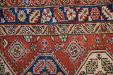 Detail of a vintage Heriz rug's serrated leaf border in navy blue, brick red, and powder blue.