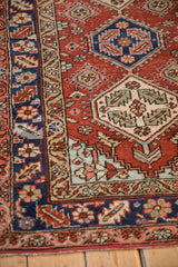 Serrated leaf and blossom motifs in the navy blue and sand borders of a vintage Persian Heriz rug.