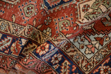 Textured low pile of a vintage Heriz rug showing geometric medallions and a floral navy blue border.
